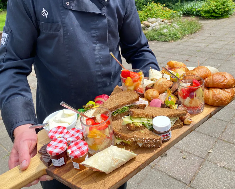 Een rijk gevulde ontbijtplank met broodjes, croissants, fruit en jam