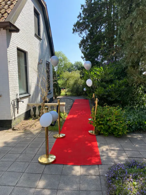 Een rode loper met ballonnen bij de ingang