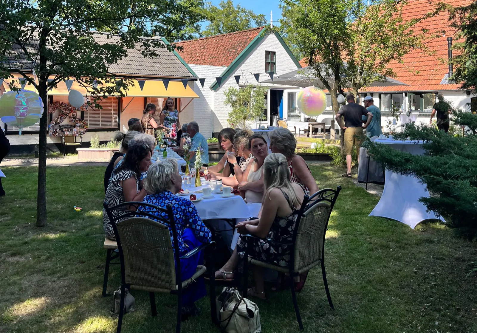 Een zonnig tuinfeest met gedekte tafels en ballonnen