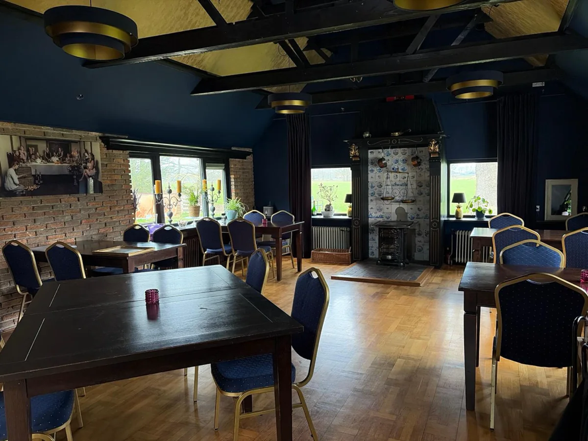 Het huiskamerrestaurant met gedekte tafels en blauwe stoelen