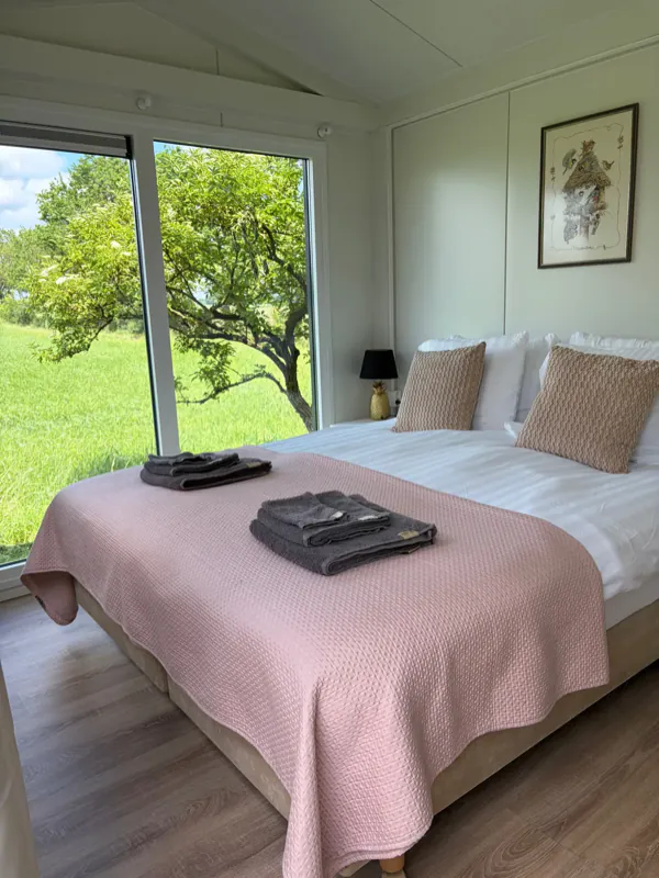 Het bed in de Tuin Suite met een groot raam naar de tuin