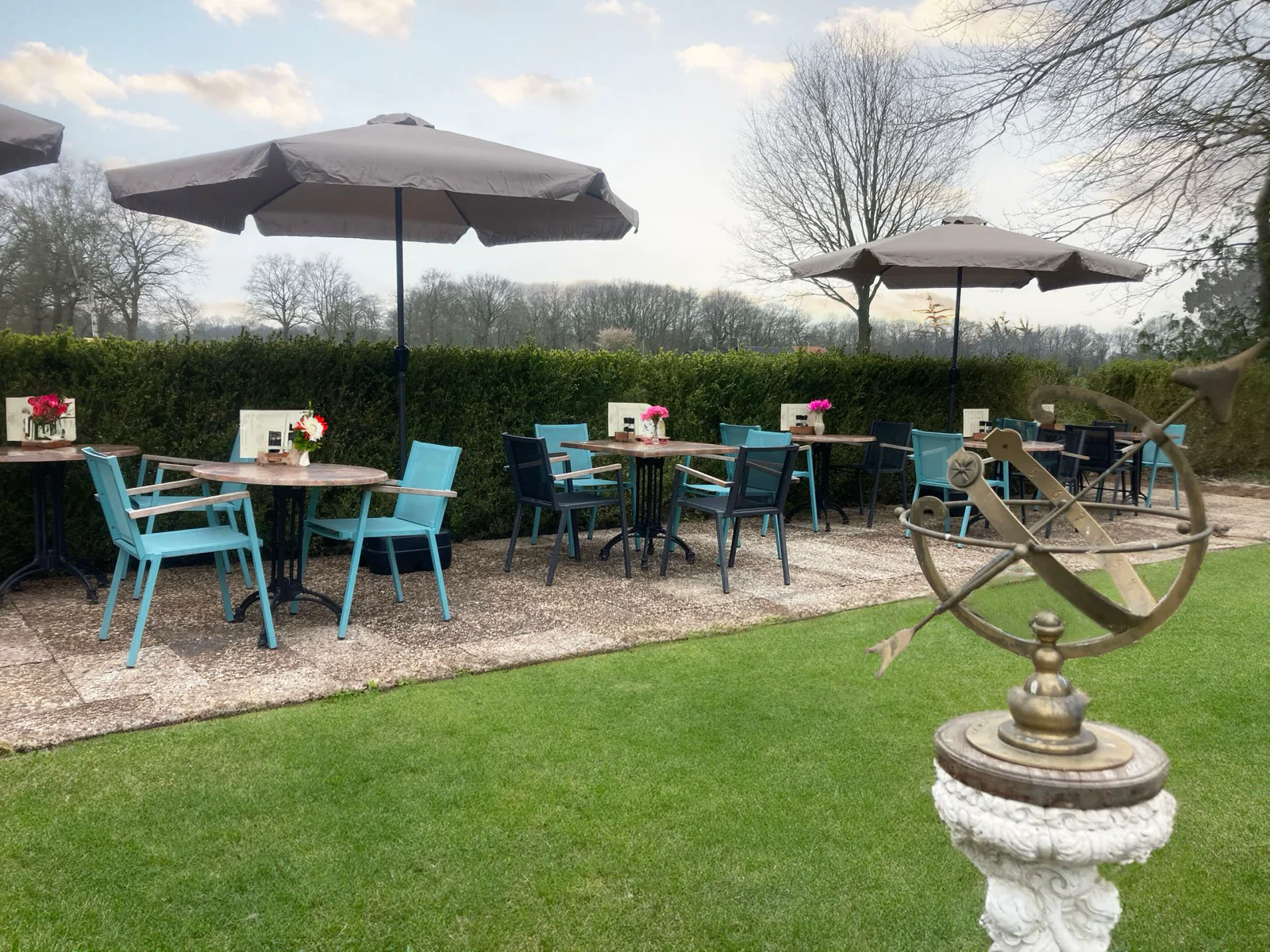 De theetuin met blauwe stoelen en een zonnewijzer